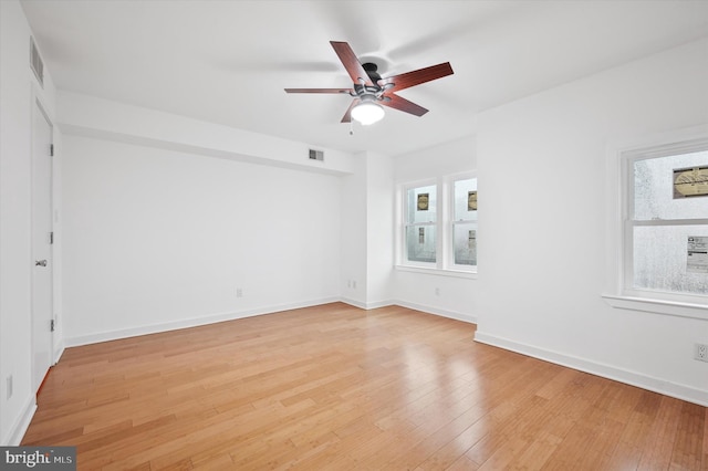 spare room with light wood-style flooring, plenty of natural light, a ceiling fan, and baseboards