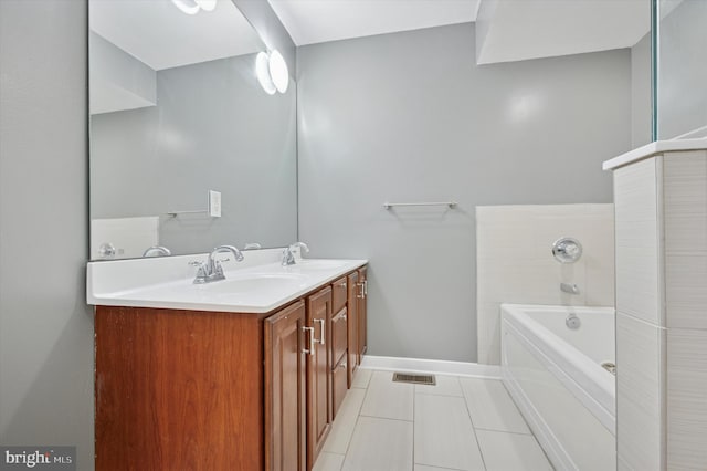 bathroom with a garden tub, double vanity, visible vents, and a sink