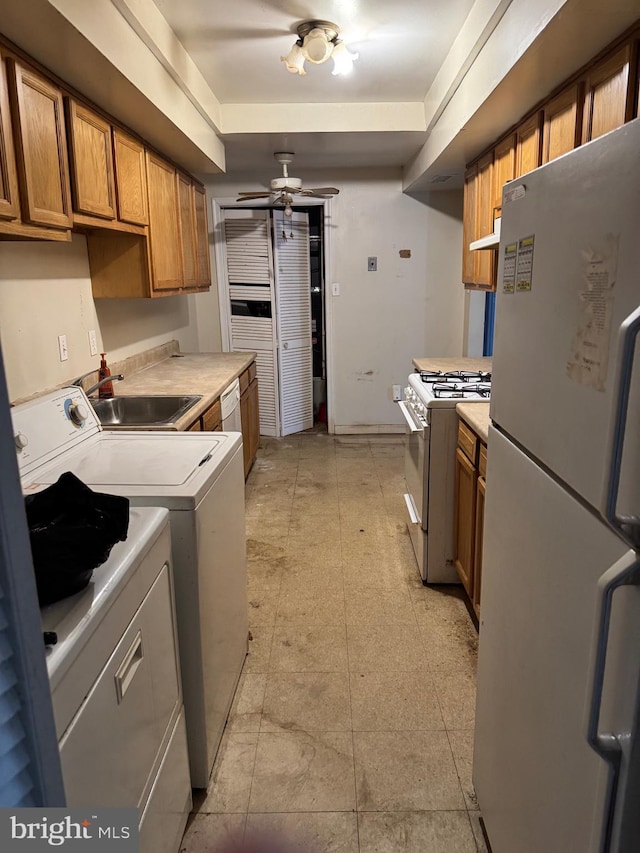 kitchen with white appliances, washing machine and dryer, light countertops, and a sink