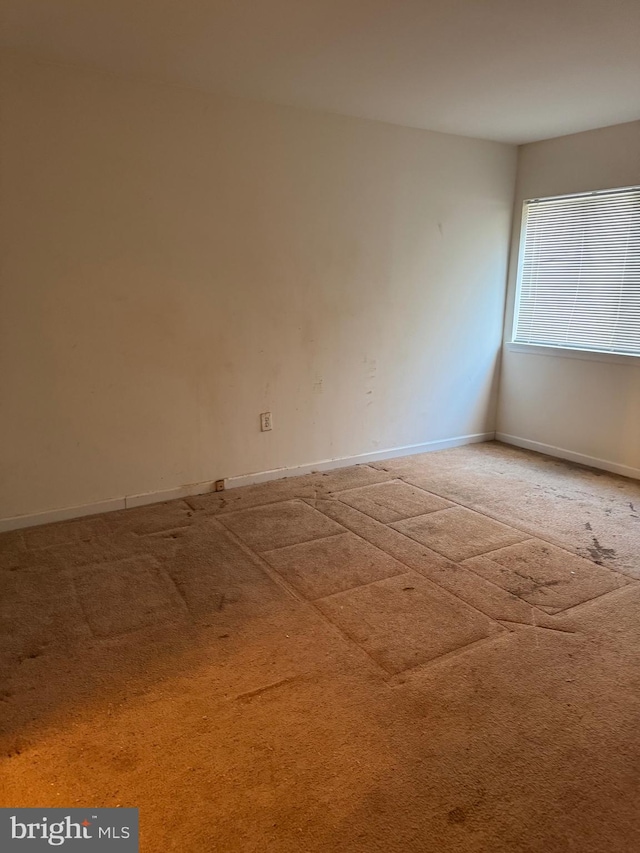 carpeted empty room featuring baseboards