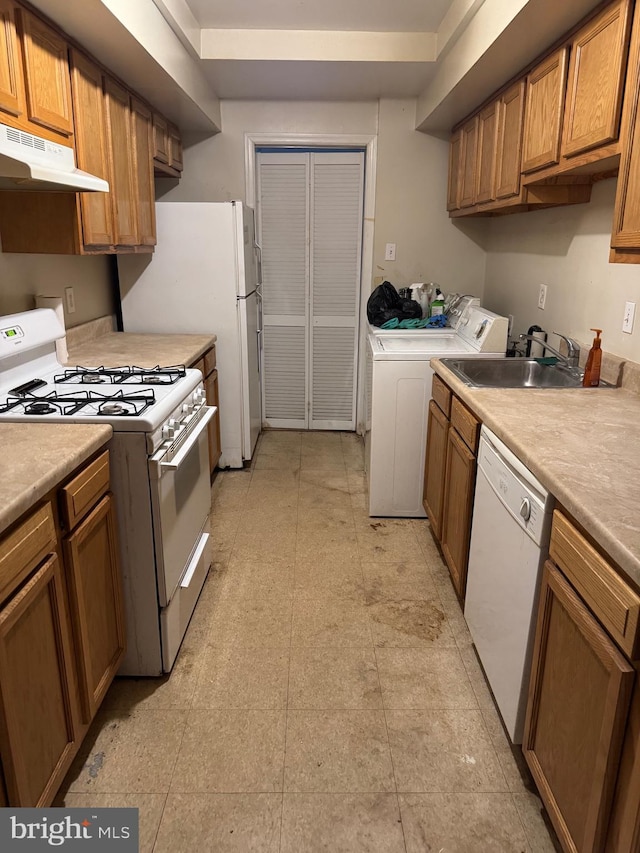 kitchen with washer and clothes dryer, under cabinet range hood, white appliances, brown cabinetry, and light countertops