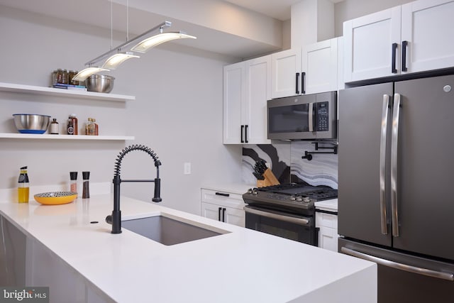 kitchen featuring a sink, light countertops, stainless steel appliances, white cabinetry, and open shelves