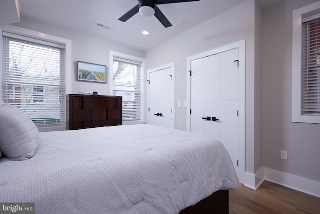 bedroom with visible vents, two closets, baseboards, recessed lighting, and wood finished floors