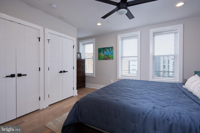 bedroom featuring a ceiling fan, baseboards, light wood finished floors, recessed lighting, and multiple closets