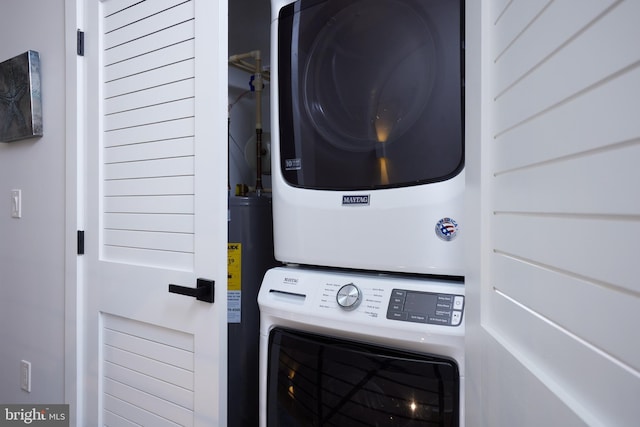 laundry area featuring laundry area, electric water heater, and stacked washer / drying machine