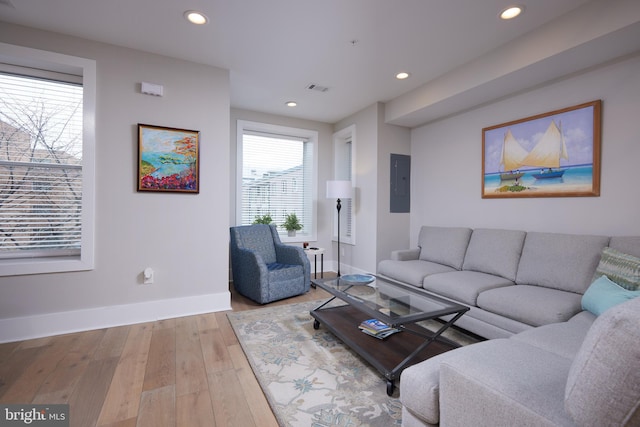 living room with hardwood / wood-style floors, electric panel, recessed lighting, and baseboards