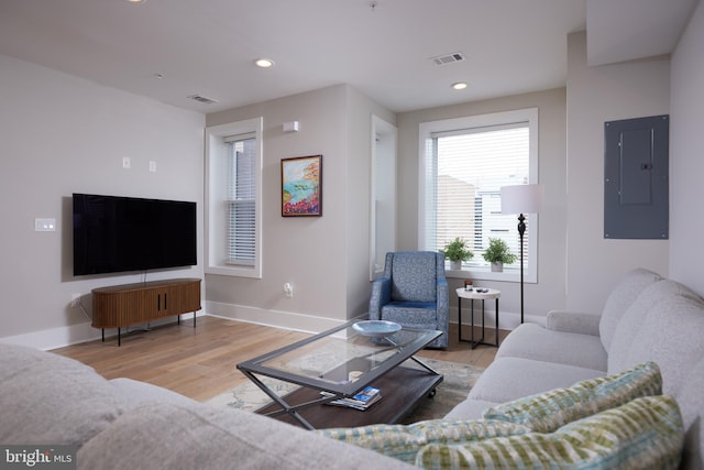 living room featuring electric panel, wood finished floors, visible vents, and baseboards