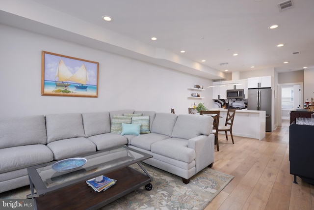 living room featuring light wood-type flooring, visible vents, and recessed lighting