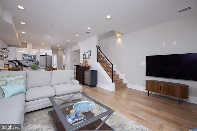 living room with stairway, light wood-style flooring, recessed lighting, and visible vents