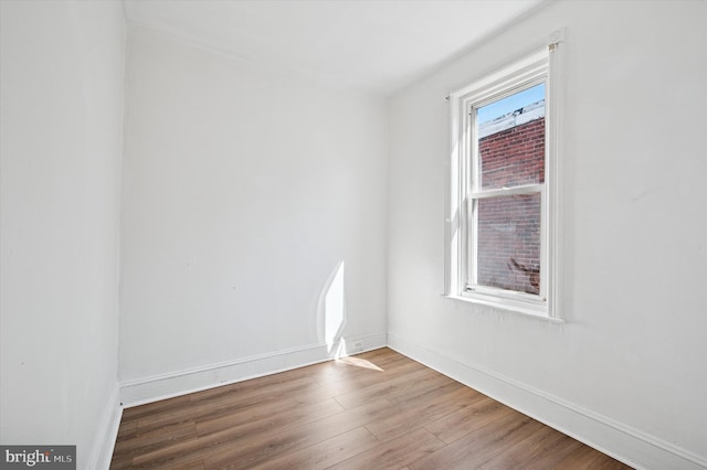 spare room with baseboards and wood finished floors