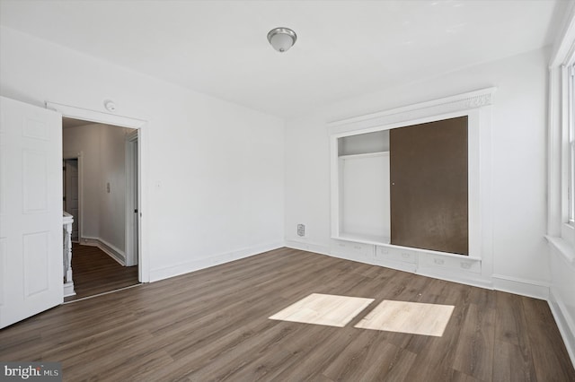 spare room featuring baseboards and wood finished floors