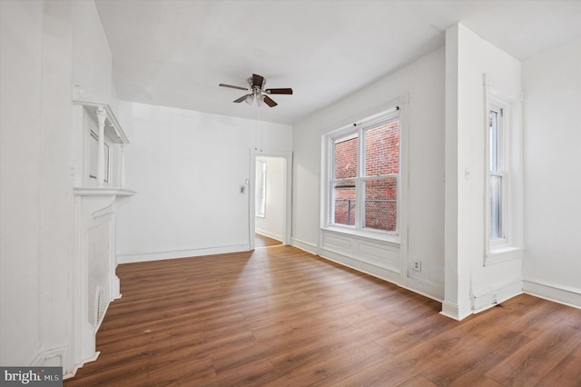 unfurnished living room featuring baseboards, wood finished floors, and ceiling fan