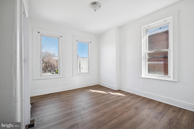 empty room with visible vents, dark wood-style floors, and baseboards