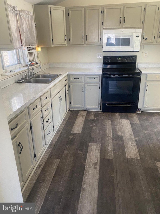 kitchen featuring white microwave, dark wood finished floors, a sink, light countertops, and black electric range oven