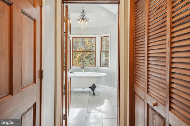 bathroom featuring a notable chandelier, baseboards, and a freestanding bath