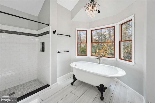 bathroom featuring a freestanding tub, lofted ceiling, baseboards, and a tile shower