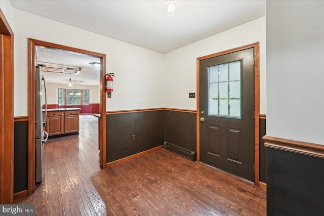 entryway featuring baseboard heating, dark wood finished floors, and wainscoting