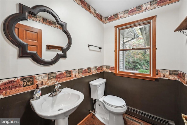 bathroom featuring wood finished floors, visible vents, a sink, a baseboard heating unit, and toilet