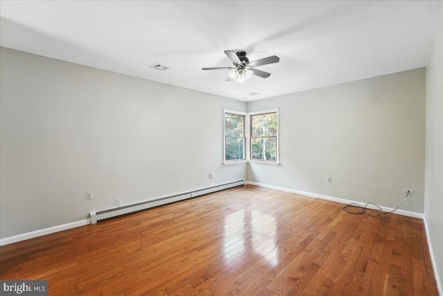 empty room with baseboards, a baseboard heating unit, wood-type flooring, and visible vents