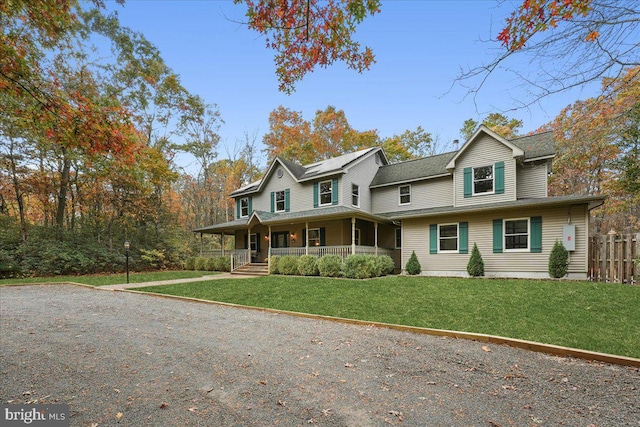 view of front of property with covered porch, a front yard, and fence