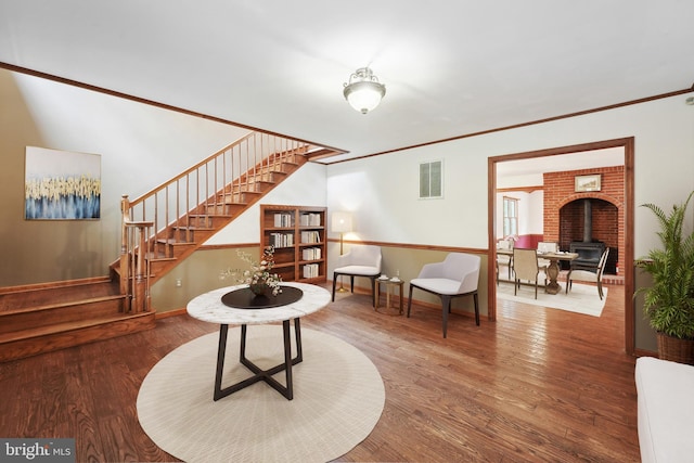 sitting room featuring visible vents, wood finished floors, a wood stove, and stairway