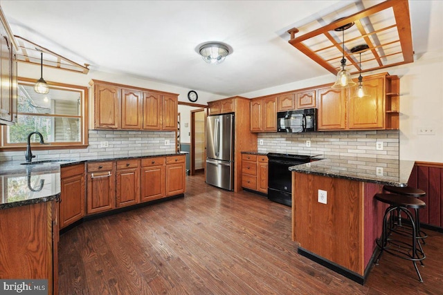 kitchen featuring black microwave, a peninsula, freestanding refrigerator, electric range, and a sink