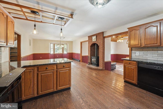 kitchen with dark wood finished floors, a wainscoted wall, a wood stove, and black dishwasher