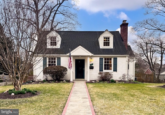 cape cod house with brick siding, a chimney, a front yard, and fence