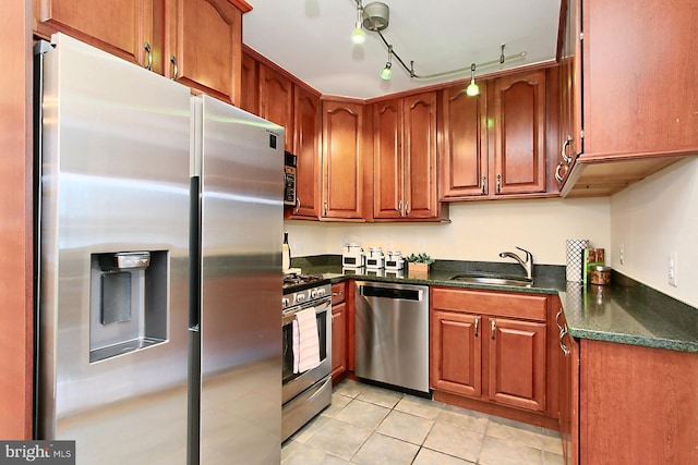 kitchen with a sink, dark countertops, stainless steel appliances, brown cabinetry, and light tile patterned floors