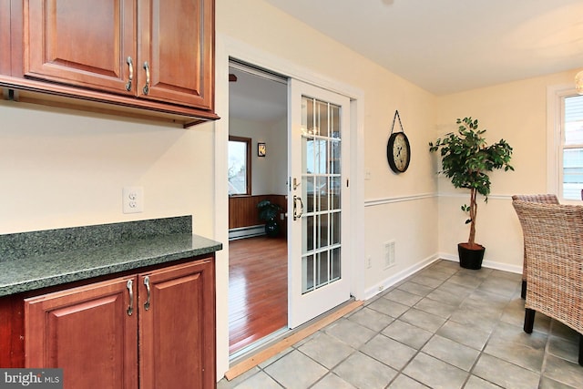 kitchen featuring visible vents, brown cabinets, dark countertops, light tile patterned flooring, and a baseboard radiator