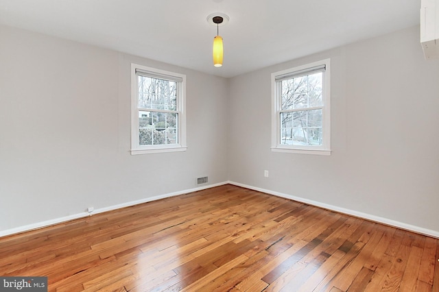 spare room featuring plenty of natural light, baseboards, visible vents, and light wood-type flooring