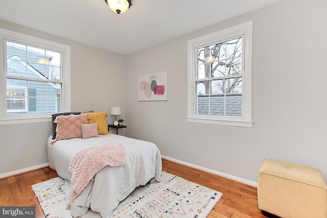 bedroom with multiple windows, baseboards, and wood finished floors