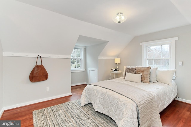 bedroom featuring lofted ceiling, baseboards, and wood finished floors