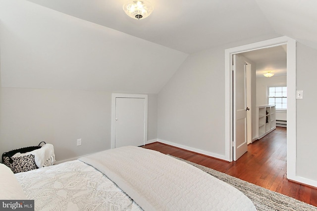 bedroom with baseboards, lofted ceiling, baseboard heating, and wood finished floors