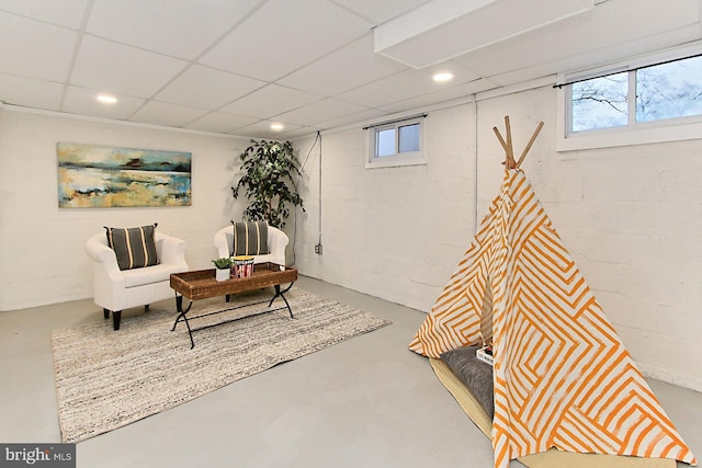 sitting room featuring a wealth of natural light, concrete block wall, concrete floors, and recessed lighting