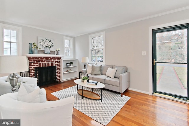 living room featuring crown molding, a brick fireplace, wood finished floors, and baseboards