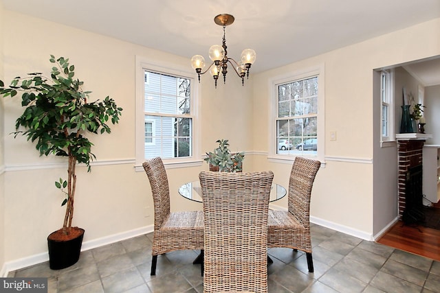 dining area featuring baseboards, a notable chandelier, and a fireplace