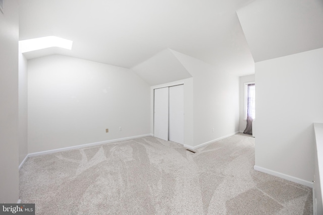 additional living space featuring lofted ceiling with skylight, baseboards, and carpet floors