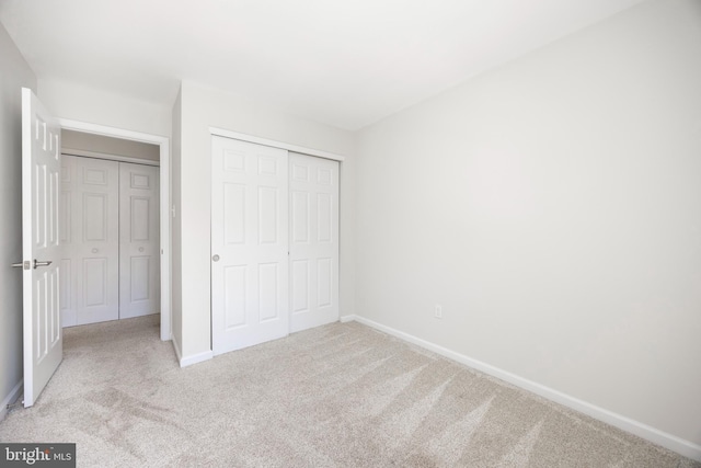 unfurnished bedroom with a closet, baseboards, and carpet