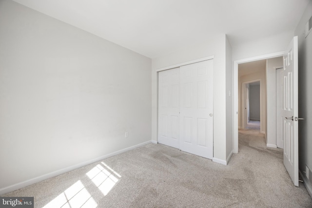 unfurnished bedroom with carpet flooring, baseboards, and a closet