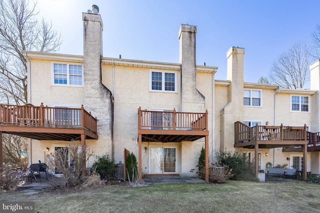 back of property featuring stucco siding, a lawn, and a chimney