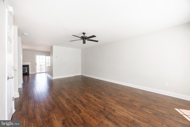 unfurnished living room with a glass covered fireplace, baseboards, dark wood finished floors, and a ceiling fan