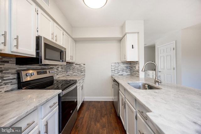 kitchen with light stone counters, dark wood finished floors, a sink, white cabinets, and appliances with stainless steel finishes