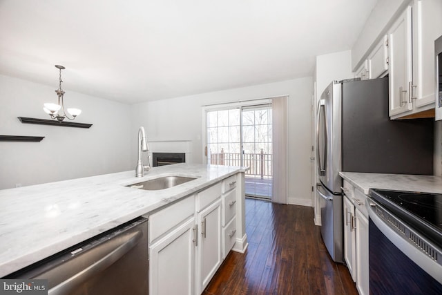 kitchen with a sink, white cabinetry, appliances with stainless steel finishes, light stone countertops, and dark wood-style flooring