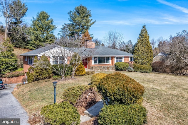 ranch-style house with a front yard, driveway, and a chimney