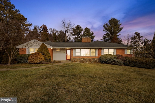 ranch-style home with brick siding, a lawn, and a chimney