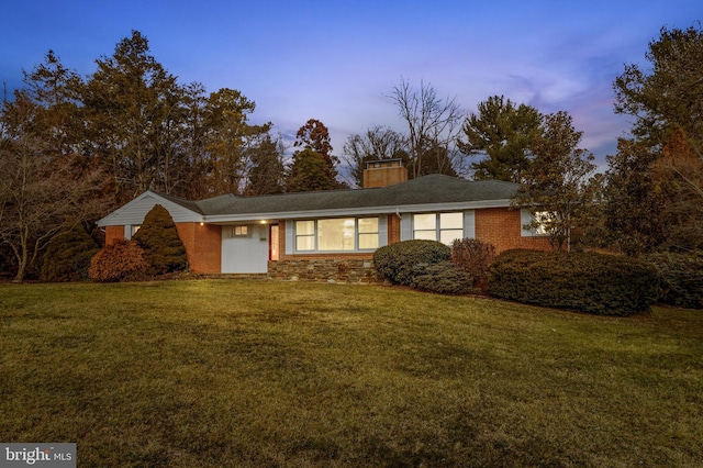 ranch-style house featuring a yard, brick siding, and a chimney