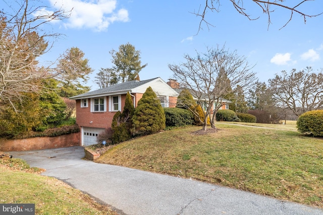 view of front facade with a front yard, driveway, an attached garage, a chimney, and brick siding