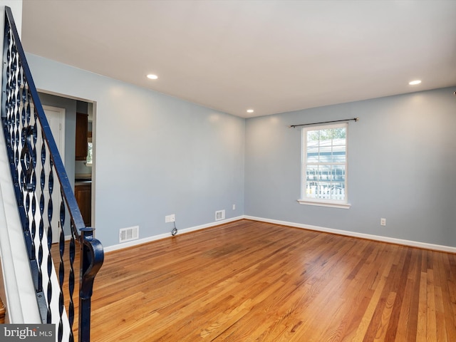 unfurnished room with visible vents, recessed lighting, stairs, and wood finished floors