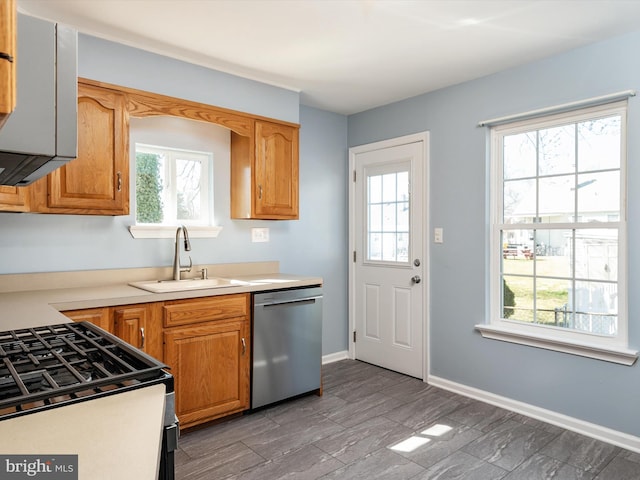 kitchen featuring a sink, stainless steel appliances, plenty of natural light, and baseboards